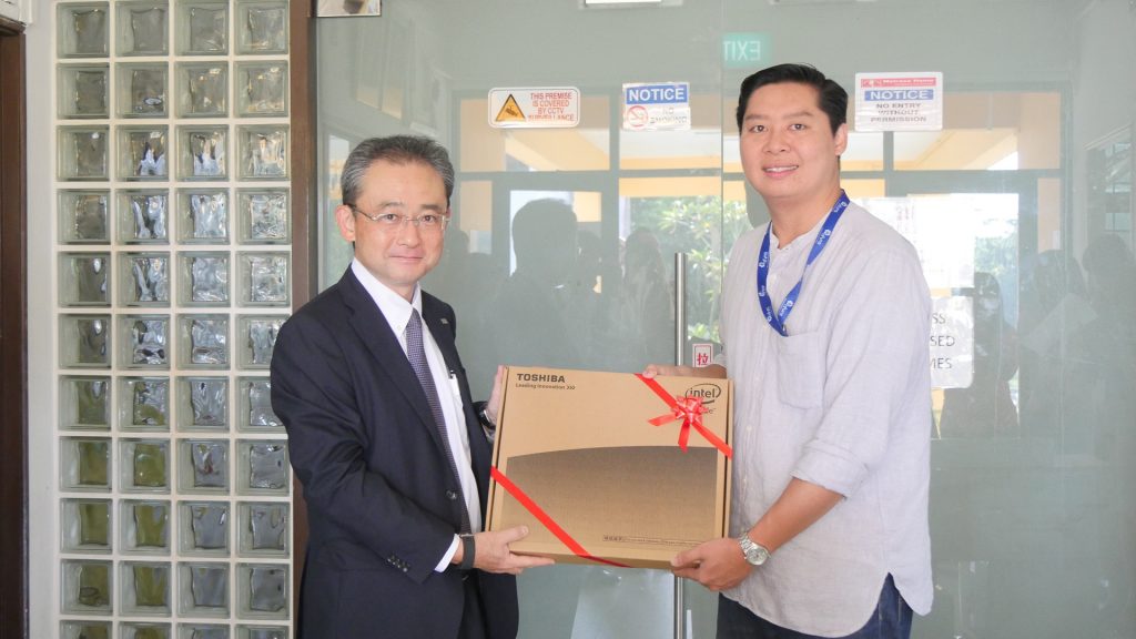 Mr Doko presenting a Toshiba laptop to Mr Frederick Low, Executive Director of Melrose Home
